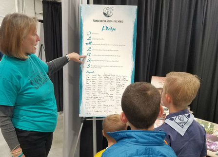 Volunteer from the Church of Scientology Denver shows the Drug-Free Pledge to younsters attending the expo.