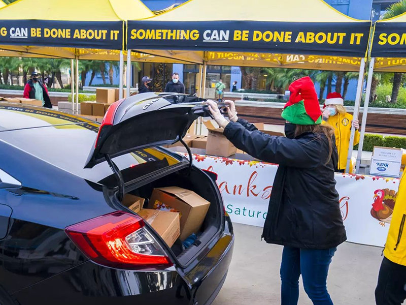Santa’s helper places a turkey in the trunk of the car at an earlier Thanksgiving turkey giveaway.