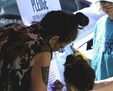 Grandmother helps her granddaughter sign the Drug-Free World pledge
