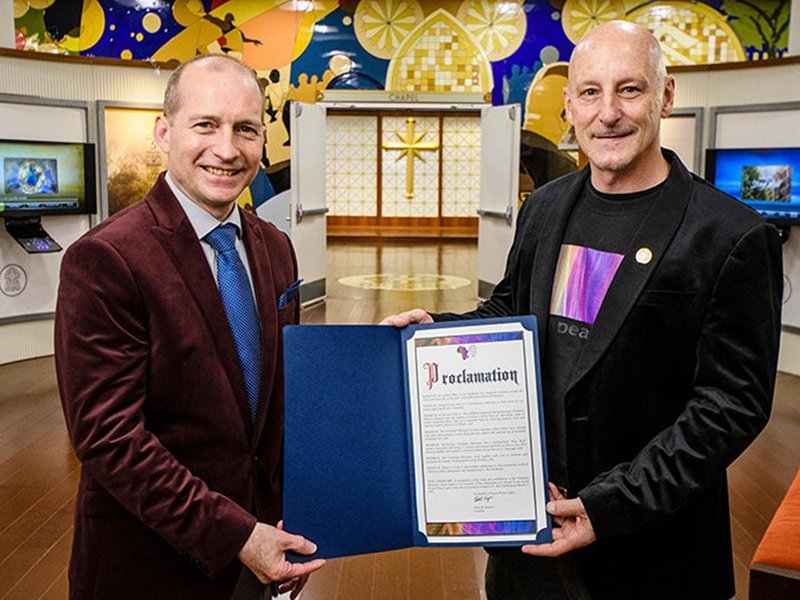 Peace Lights Founder (right) presents a representative of the Church of Scientology with a proclamation thanking Founder L. Ron Hubbard for inspiring the United for Human Rights educational initiative.